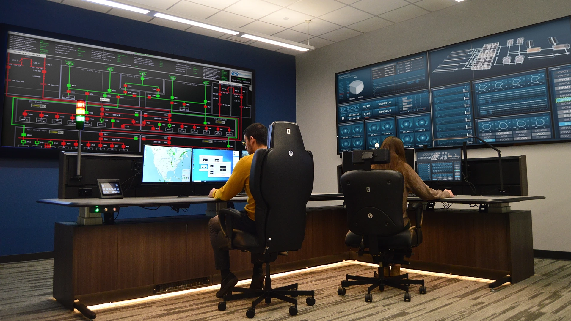 Control room operators in custom console with multiple displays and a large video wall
